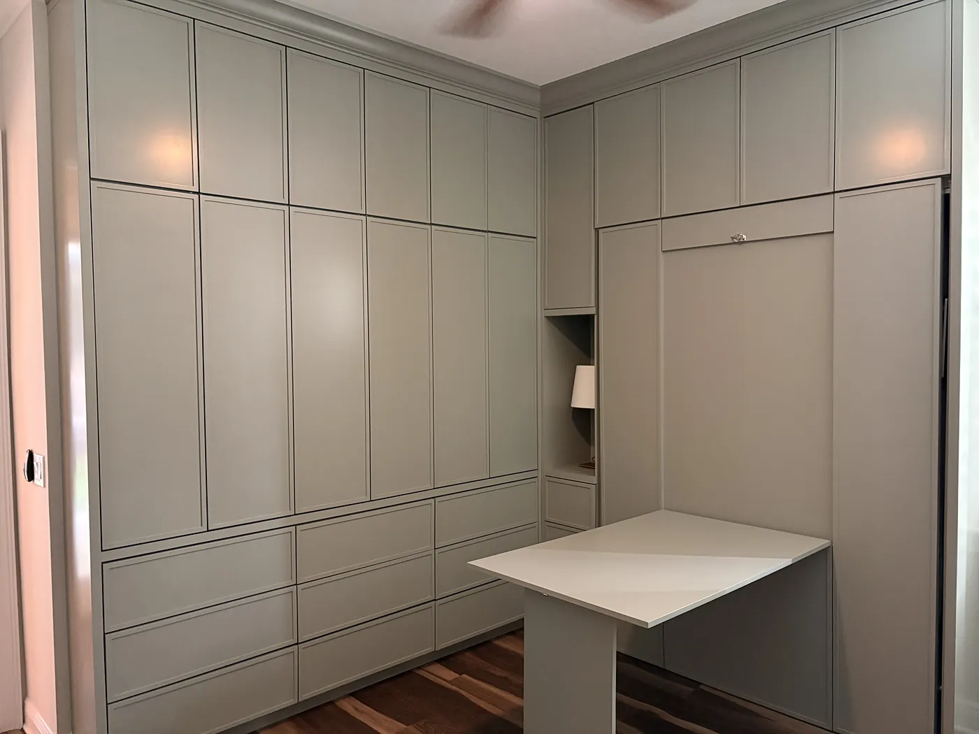 A Murphy bed and a fold down desk built into one wall of fitted wardrobes, the desk lowered