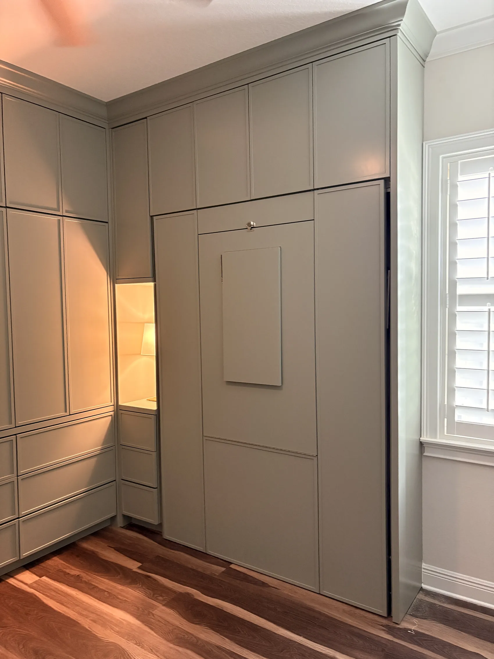 The Murphy bed closed flush into the run, its pull the only thing that gives it away, with a lit niche alongside
